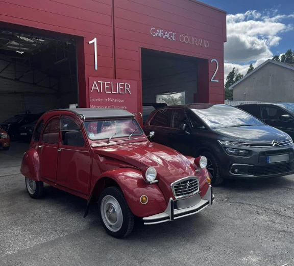 Concession automobile avec vendeur en costume bleu et cliente en robe rose portant des masques sanitaires, consultant des documents contractuels pr&egrave;s d'un v&eacute;hicule gris m&eacute;tallis&eacute;