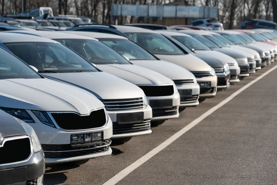 Mécanicien automobile en casquette bleue travaillant dans un garage, utilisant un outil pneumatique pour démonter une roue de voiture blanche surélevée sur pont élévateur